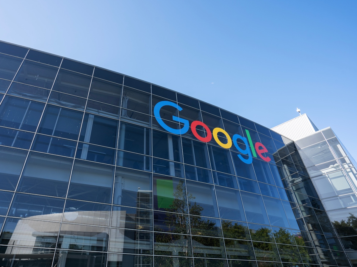Google company logo on a tall glass covered building.