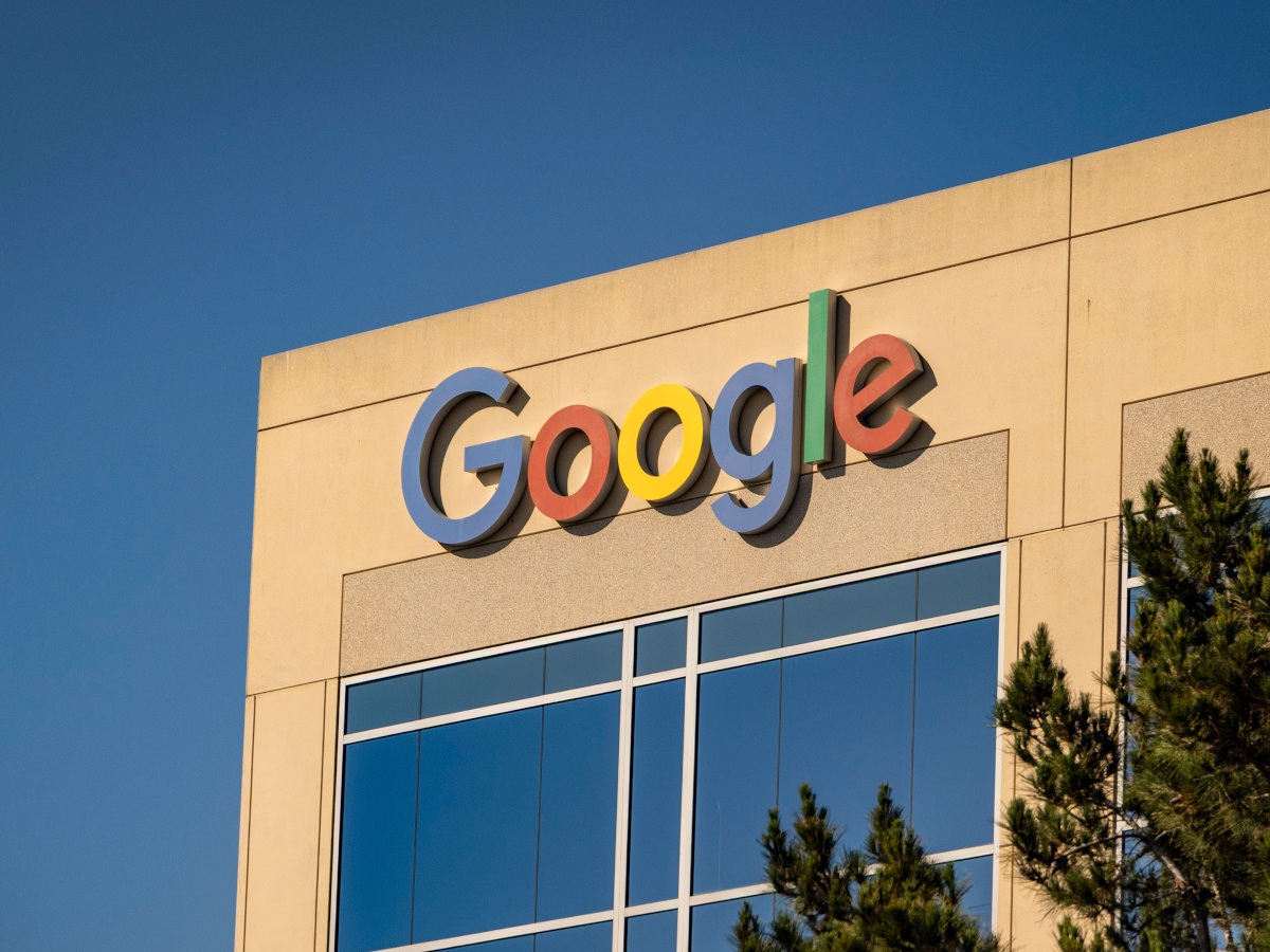 A picture of the Google sign sitting on the side of an office building with the glow from a sunset hitting it.