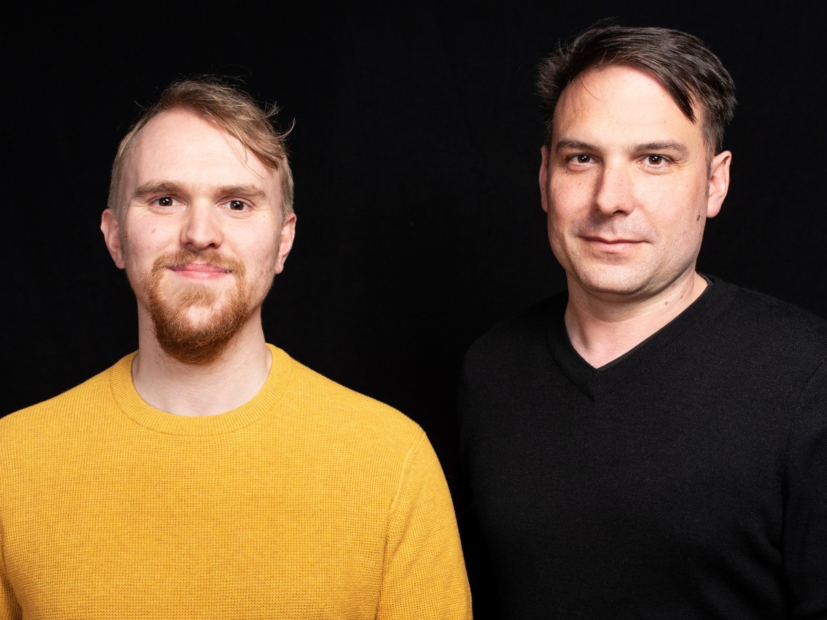 Headshots of two men standing together with a black background.
