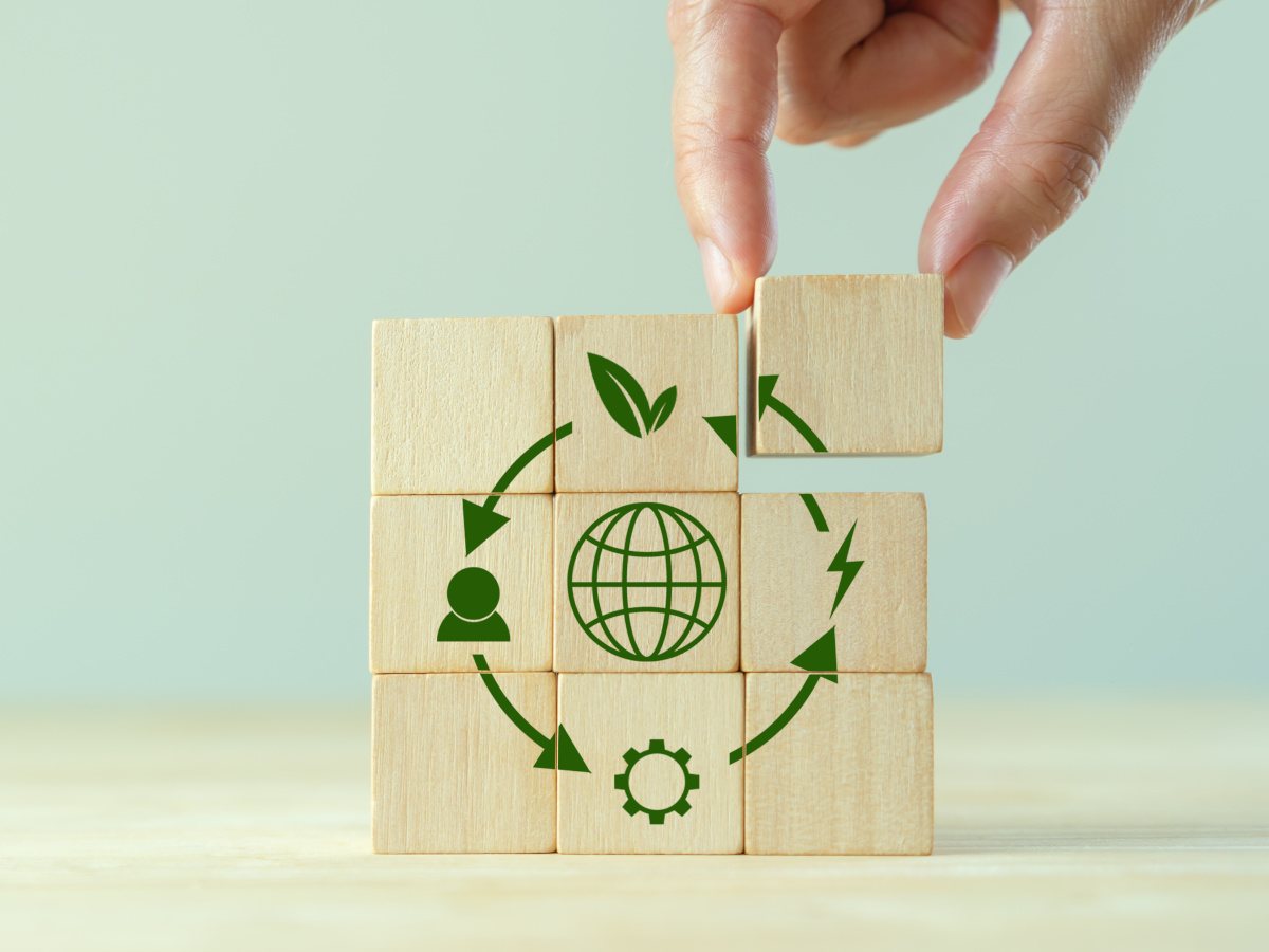 A hand putting wooden blocks completing the image of a circular economy.