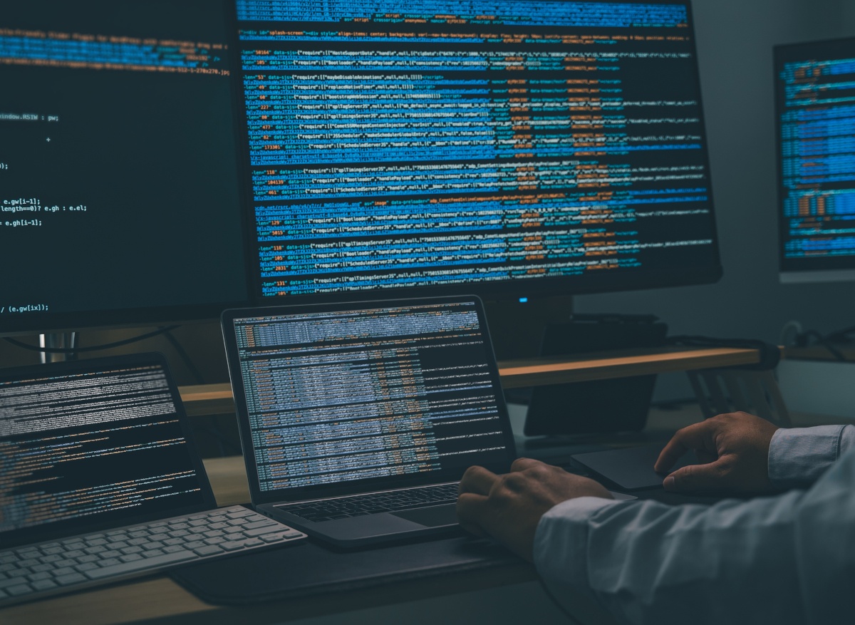 male hands and multip screens with code