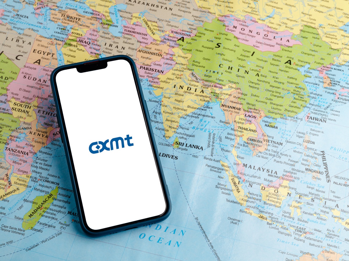 A phone with the CXMT logo, sitting a top a world map.