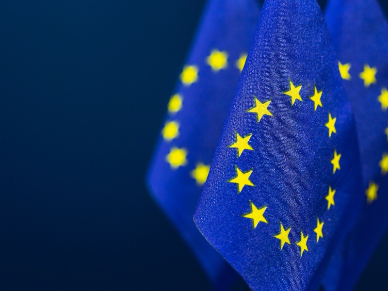 EU flags with dark blue background empty space.