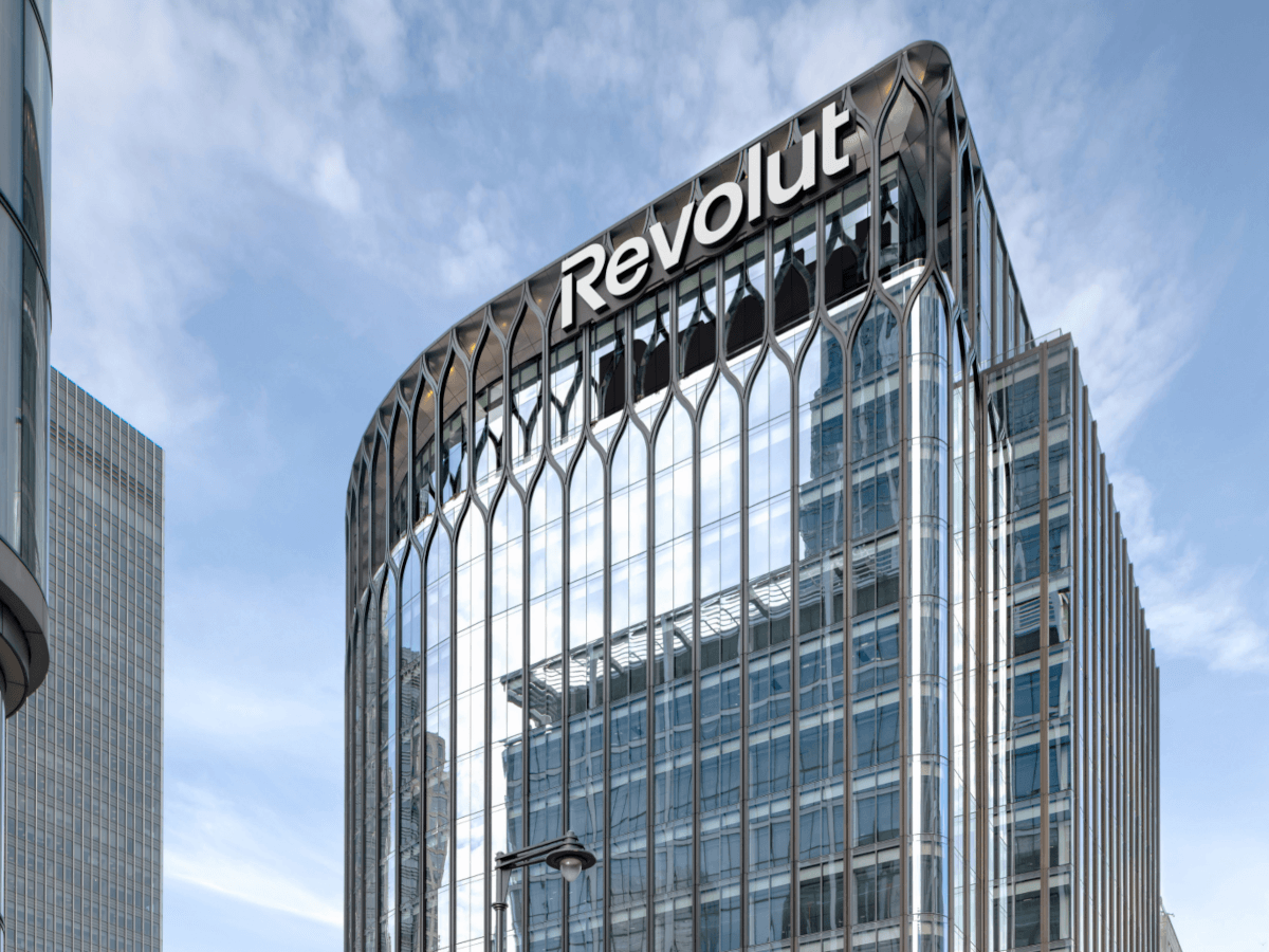 A glass building belonging to Revolut, against a blue sky.