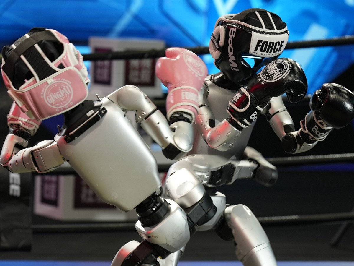 Two humanoid robots hitting each other in a boxing match.