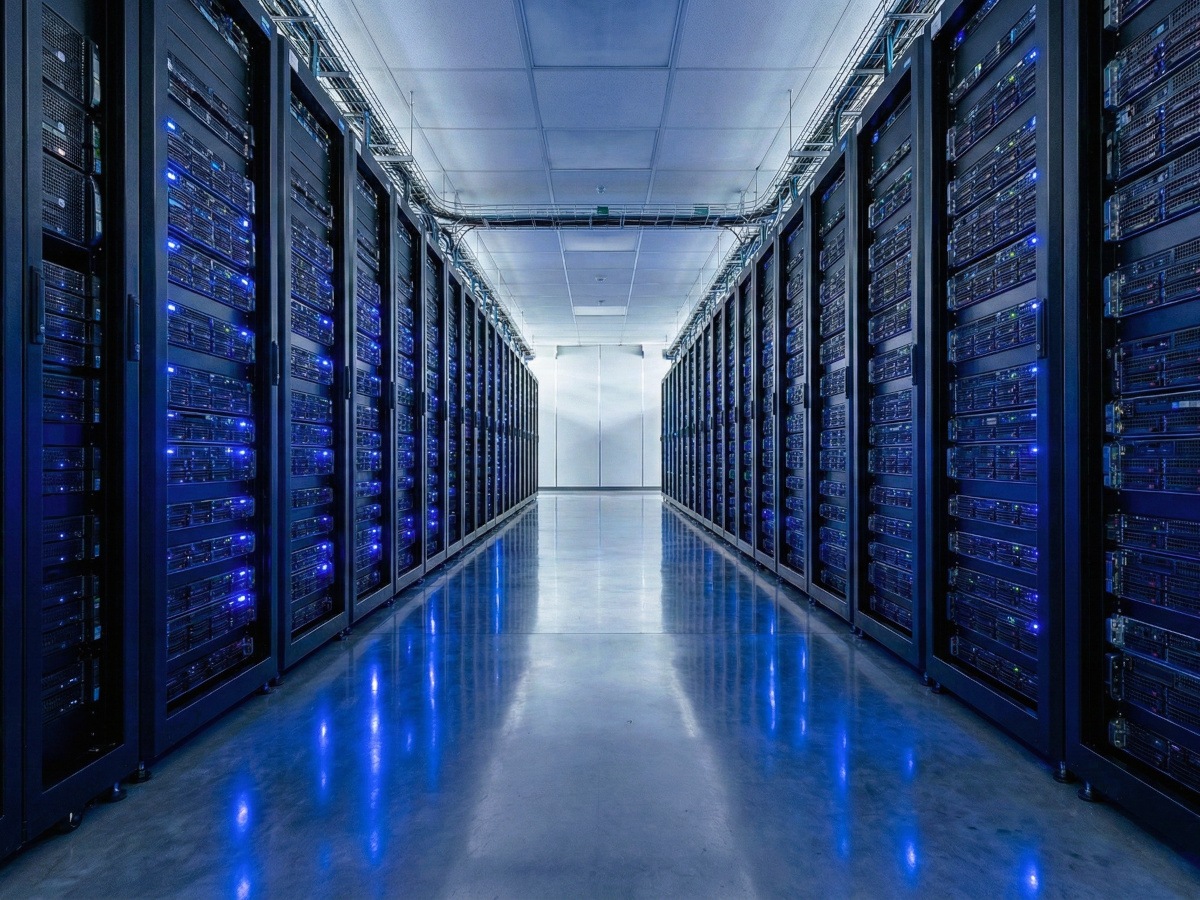 A picture of rows of data centre racks sitting in a hallway blinking with blue LEDs.