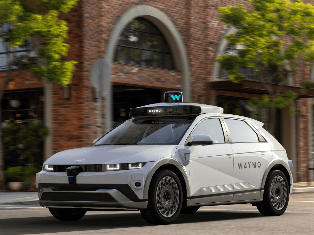 A rendering of a white Waymo vehicle on a city street.