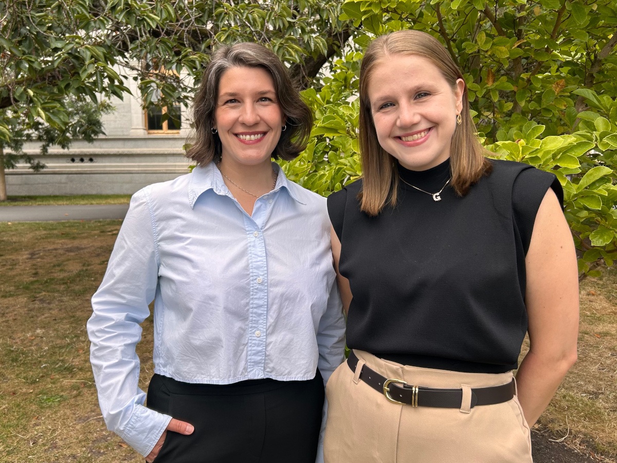 Two women in office-wear, smiling.