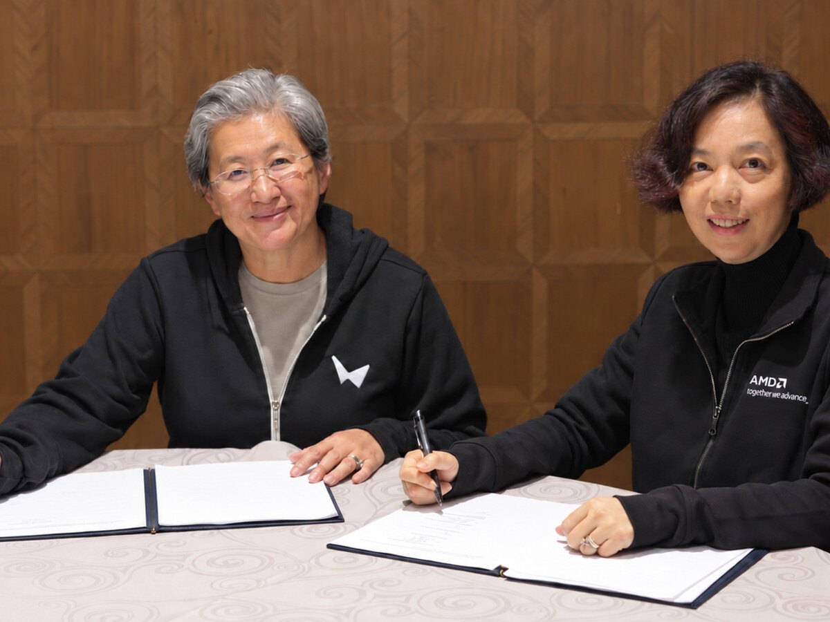 Two women in a black hoodie sitting at a desk.