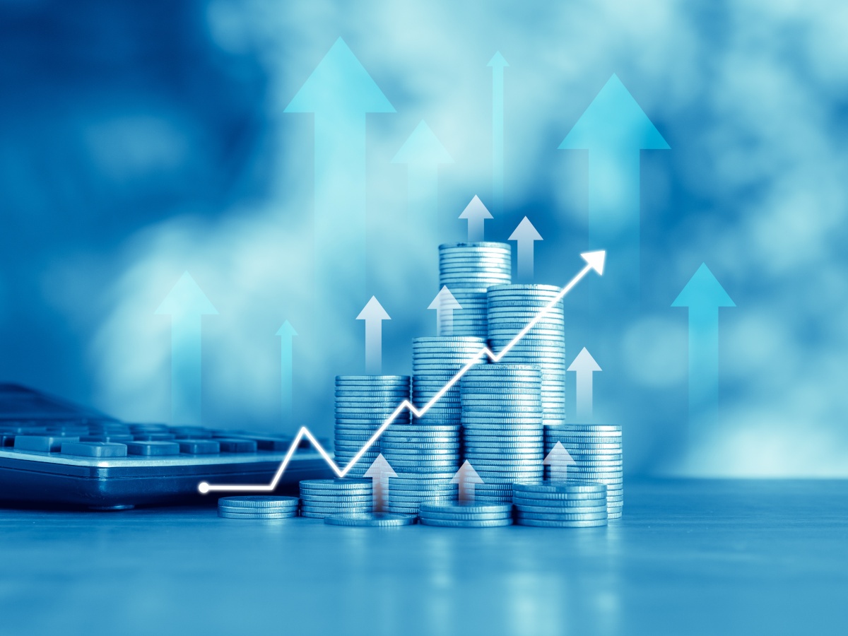 Stacks of coins with an upwards arrow over them, indicating investment.