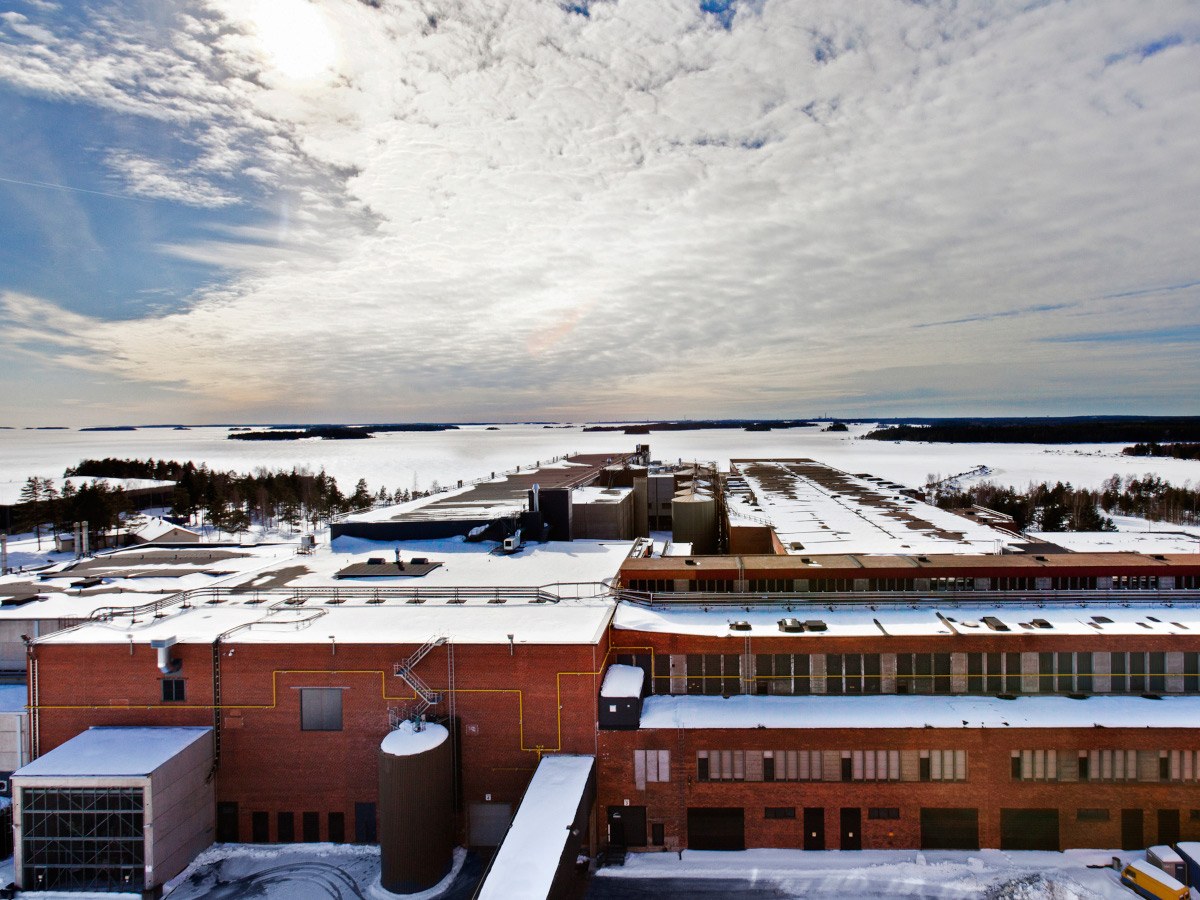 A large building campus with a cloudy blue sky and snow covering the land.