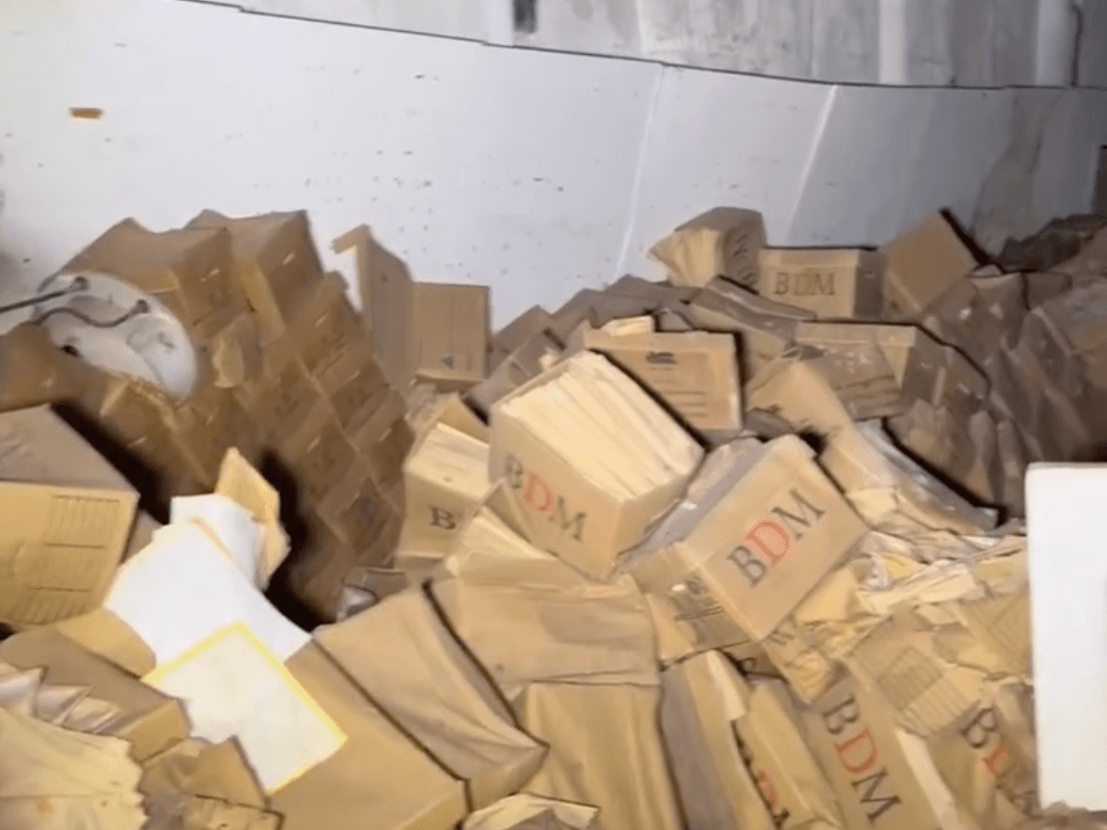 A screenshot of a video that shows dozens of cardboard boxes strewn across a basement.