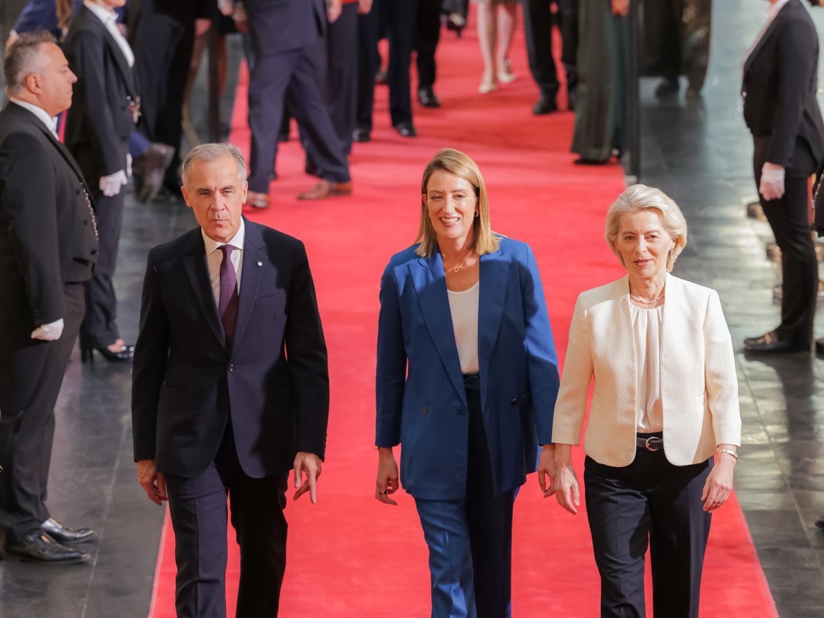 Three people walking down a red carpet with a crowd around them.