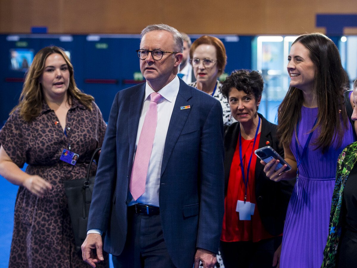 A man in a suit standing around a group of people looking at him.