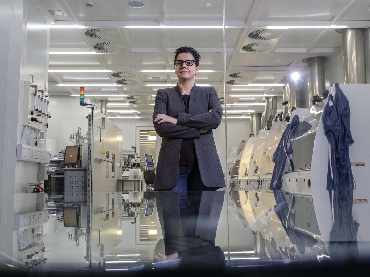 A person with short hair in a suit standing in a laboratory.