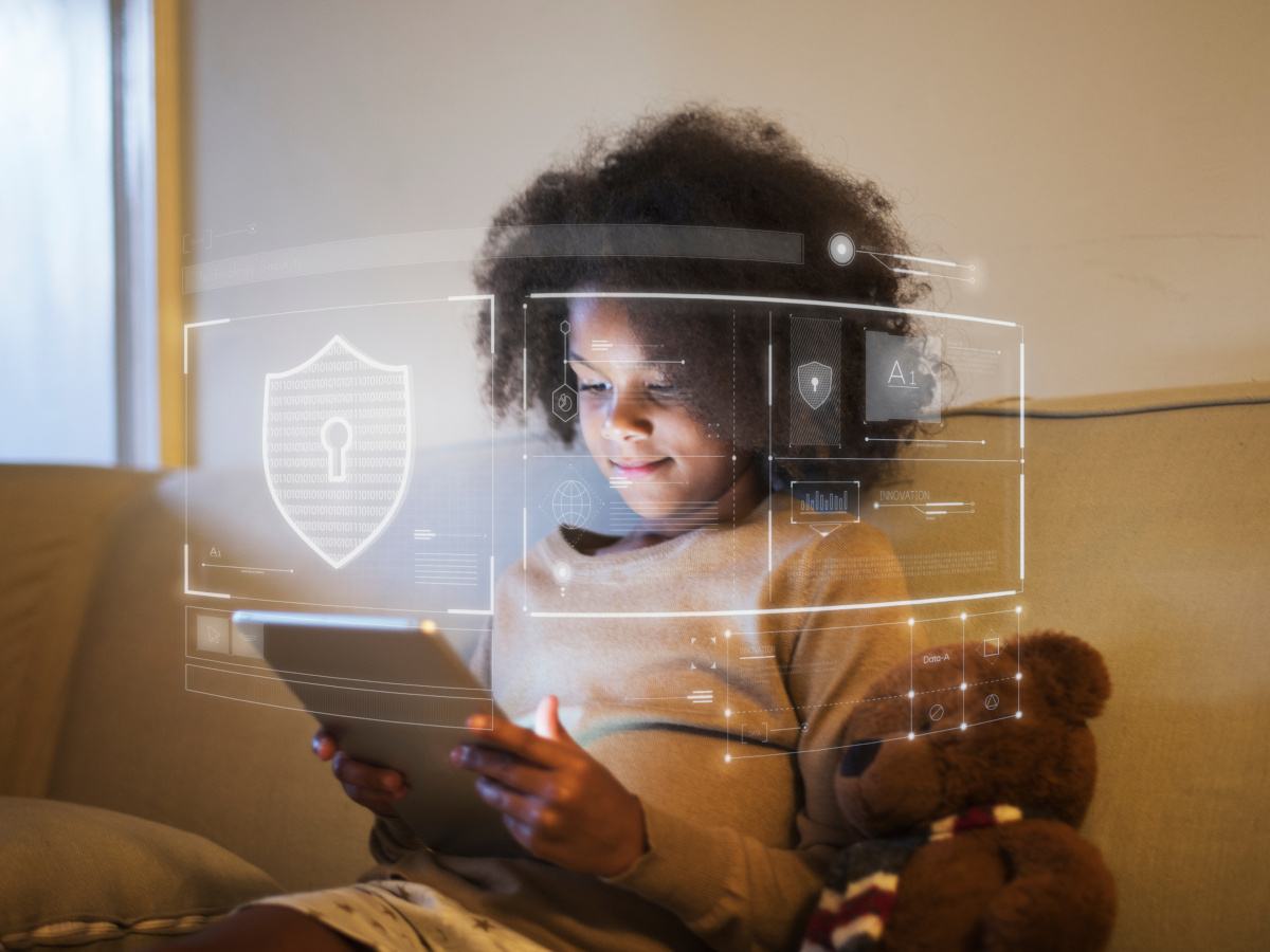 A young black child with natural dark hair looking at an iPad surrounded by safety icons.