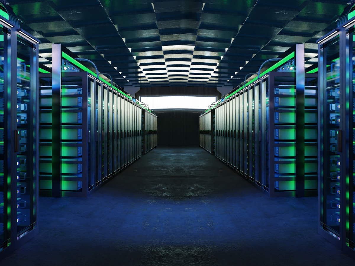 An industrial room containing rows of computing racks either side of a corridor.
