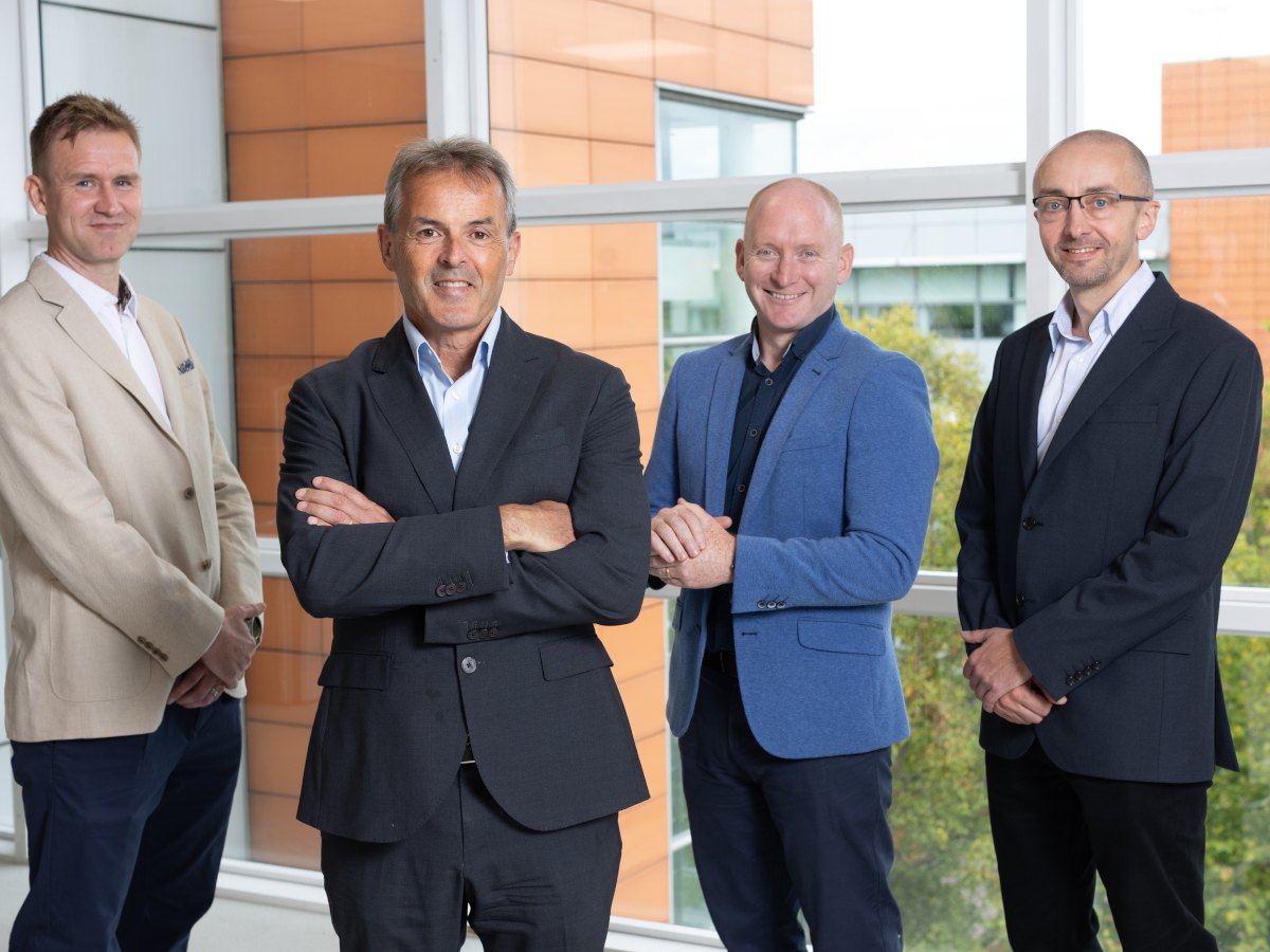 Four middle-aged white men in casual business attire in an office setting.