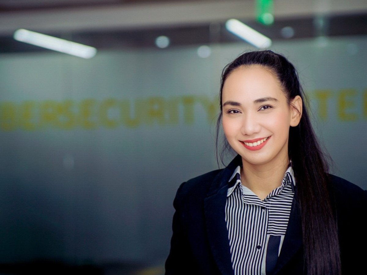A young Asian woman with long black hair in business attire, in an office background.