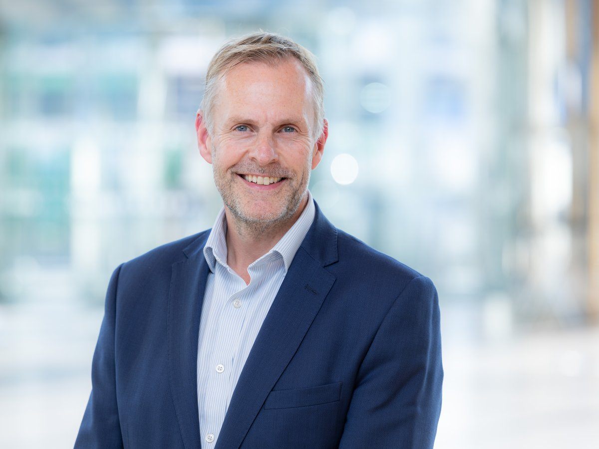 A middle-aged white man in business attire against a blurred background.
