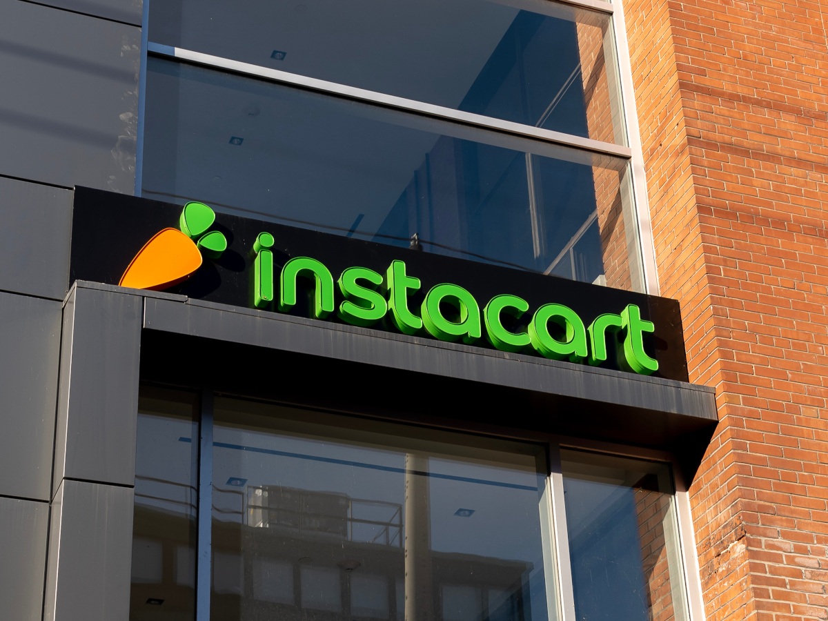 The Instacart sign, with a carrot logo alongside it, sits on a building above the entrance.