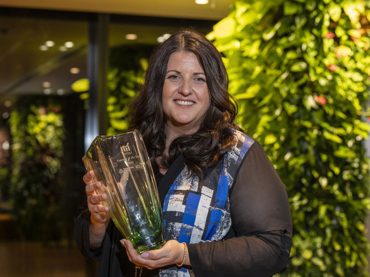 A woman with brown hair holding a clear trophy.