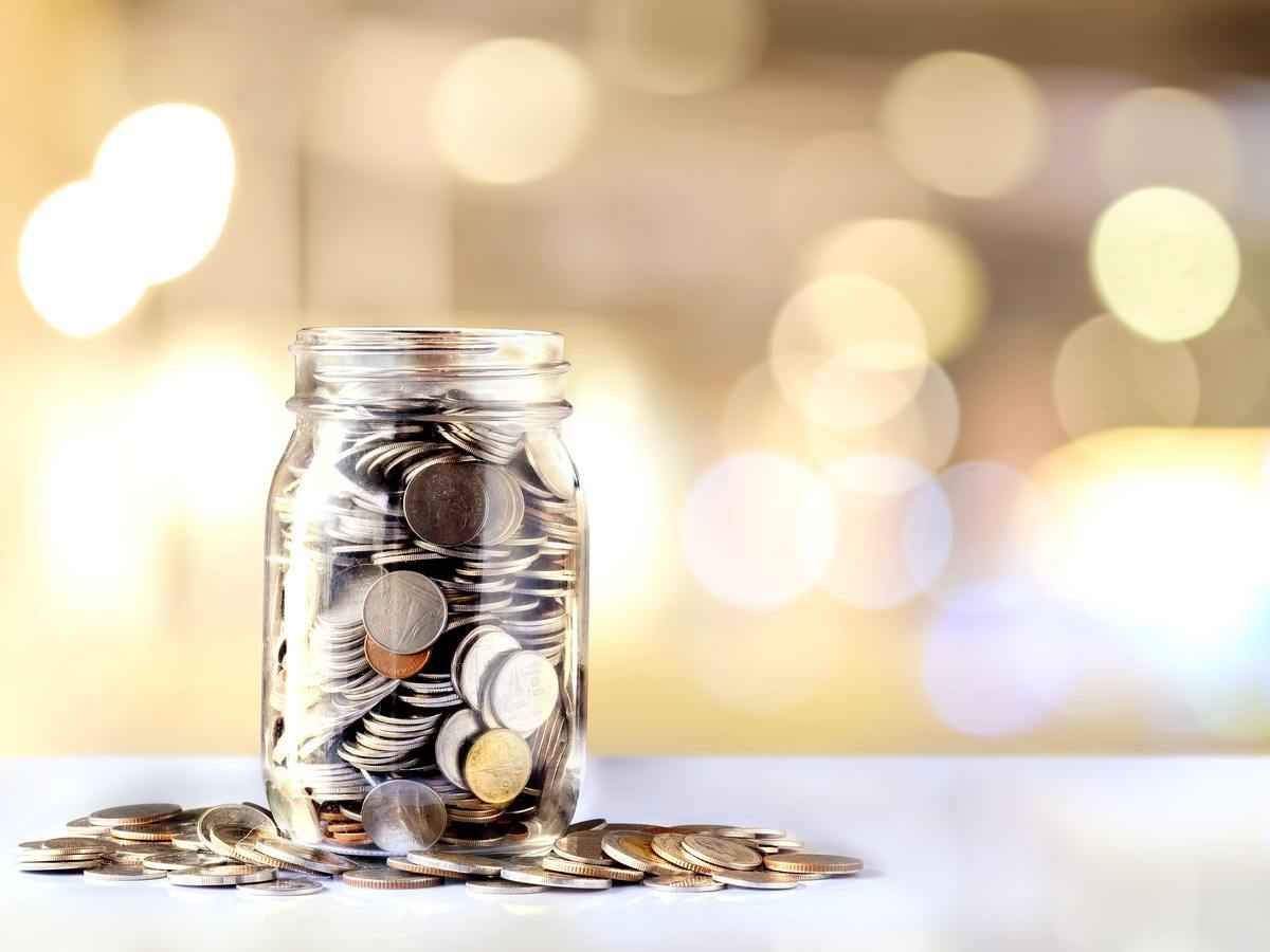 An overflowing jar of coins to symbolise funding.