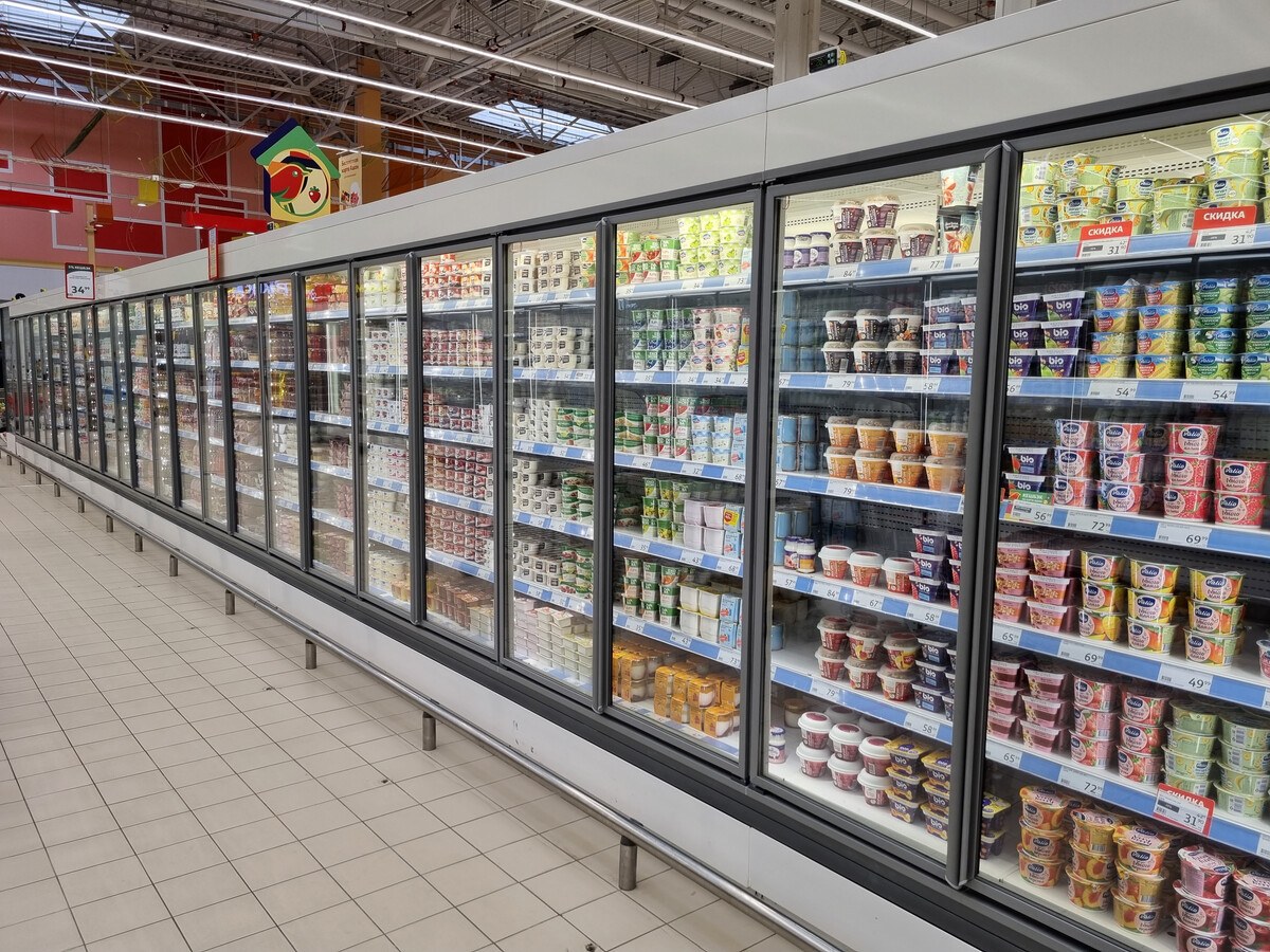 A supermarket aisle with rows of refrigerators.