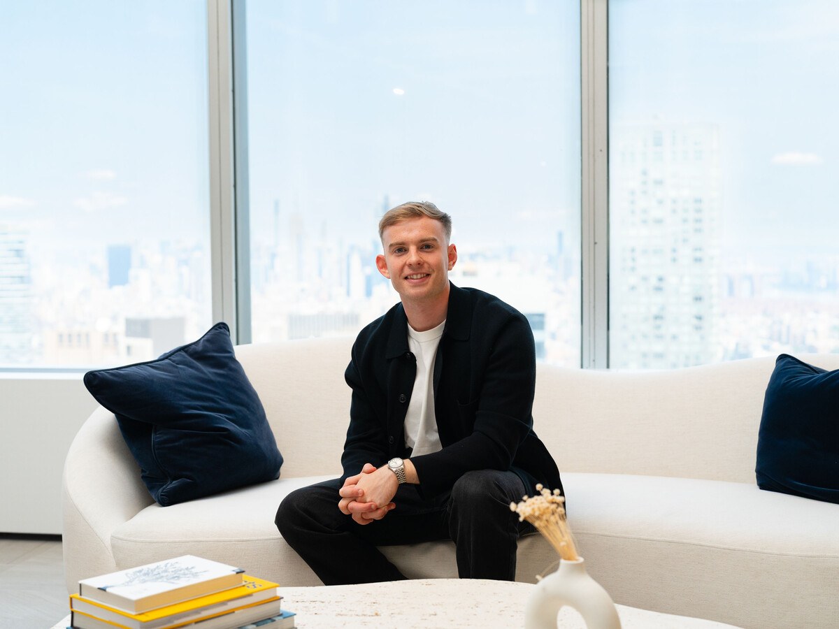 A man in black trousers and a blazer in a sofa.