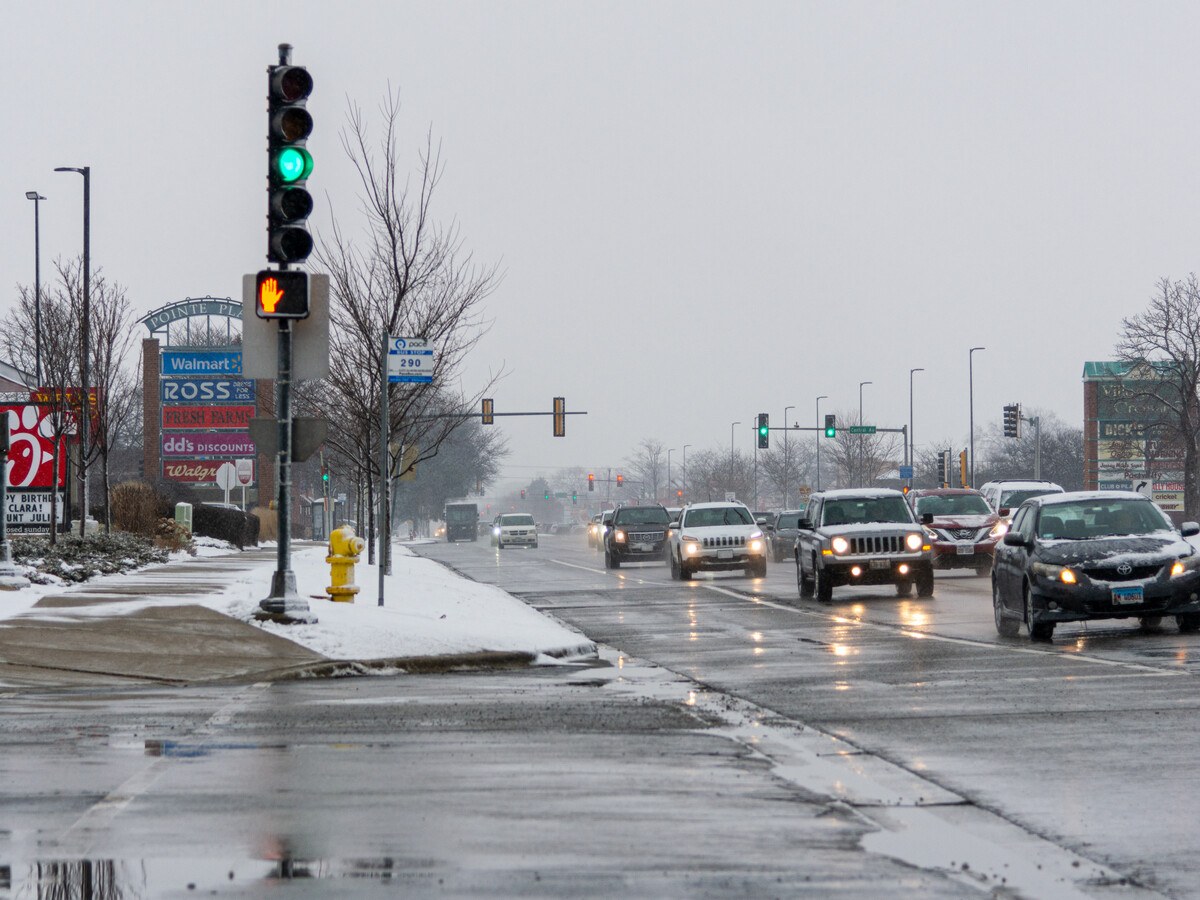 A wide icy road with a few cars.